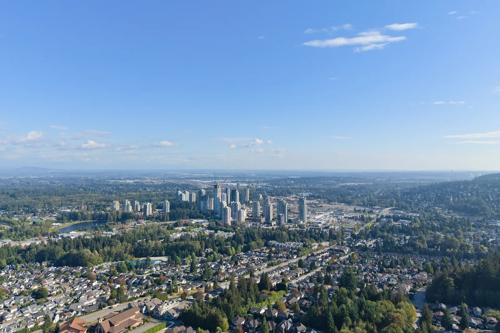 Coquitlam Town Centre towers seen across wooded residential neighbourhoods on a clear day